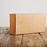 Craft unlabeled cardboard package box presented on stressed brushed wooden table, isolated on white background